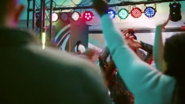 Sahnede kulaklığı olan genç bir adam elektronik müziği DJ istasyonuna koyuyor, dans pistindeki arkadaşlarıyla eğleniyor. Disko partisinde kendini kötü hisseden bir erkek. El kamerasıyla..