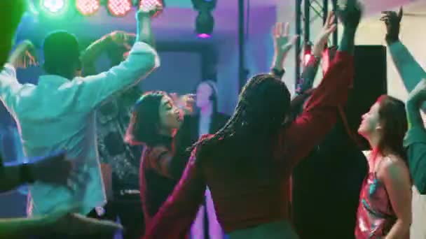 时髦的人在夜总会跳舞 在舞台上为Dj和电子音乐组合欢呼 一群人在舞池里用不同的颜色和音频面板进行聚会和跳跃 三脚架射击 — 图库视频影像