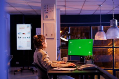 Masa başında oturan yönetici yeşil ekran analiz ediyor izole ekran ile krom anahtar bilgisayarı taklit ediyor. Girişim ofisindeki şirket stratejisinde fazla mesai yapan iş kadını