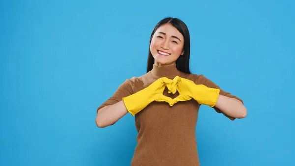 Happy Asian Maid Wearing Yellow Gloves While Doing Heart Shape — Stok fotoğraf