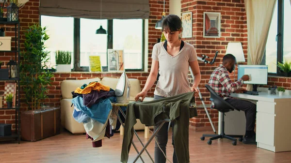女人们洗衣服后在公寓里熨烫衬衫 用蒸汽熨斗去除衣服上的皱纹 年轻妇女做家务活 周末料理家务 — 图库照片