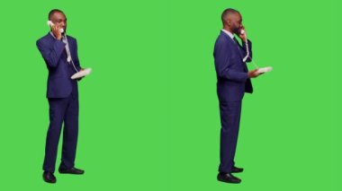 Sabit hattan konuşan genç bir işadamı stüdyoda kabloyla eski telefon görüşmeleri yapıyor. Şirket çalışanı telefon hattında sohbet ediyor, tüm gövde yeşil ekran arkaplan.