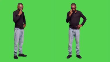 Stüdyoda doğru kararı vermeyi düşünen düşünceli genç bir adam tüm vücudunun yeşil ekranda düşünceli olduğunu düşünüyor. Erkek model kameraya yeni fikirler yüklüyor, kot pantolonlu iyimser kişi.