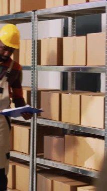 Dikey video: Depo ekibinin depo odasındaki nakliye listesini incelemesi, perakende satışından önce stok envanter ve tedarik zincirine bakması. Depoda mal siparişlerini kontrol eden genç çalışanlar.