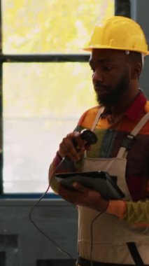 Dikey video: Depo işçisi kargo stoğunu perakende mağaza tarayıcısıyla tarıyor, siparişleri tabletle kontrol ediyor. Depo çalışanı dağıtıma hazırlanıyor, imalat sektöründe çalışıyor.