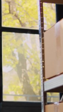 Dikey video: Depo çalışanı, depo lojistiği için tarayıcı ve tablet kullanarak barkodları tarıyor, kargo stoklarını kontrol ediyor. Delikanlı mal stoklarını kontrol ediyor, depo teftişi yapıyor..