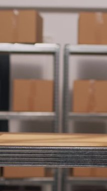 Dikey video: Afro-Amerikalı bir adam depoda kutuları ayırıyor, raflarda ve raflarda ürünleri düzenliyor. Depoda mal ve ürün paketleri taşıyan bir erkek çalışan. Üçayak atışı.