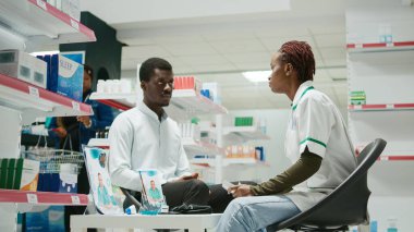 Male customer asking pharmacist about pills medicine, looking at packages of medicaments and supplements. Client and specialist talking about vitamins cure from pharmacy shop.