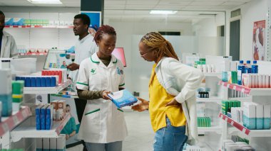 Customer with back pain asking medic about pills, looking to buy pharmaceutical products to cure physical problem. Woman talking to pharmacist about healthcare medicine and treatment.