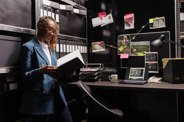 非裔美国女警察调查员在办公室阅读案件档案 私家侦探持有的文件夹和分析调查报告近板与线索连接方案 — 图库照片