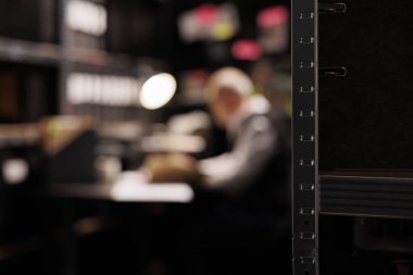 Kanıt odası, federal belgelerle dolu metalik raflarla dolu. Arka planda suç davasında fazla mesai yapan eski bir polis memuru, soruşturma raporunu analiz ediyor. Seçici odak kavramı