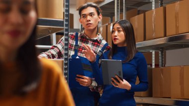 Asyalılar hisse senetlerini tablet ve kağıtlarla analiz ediyor, ticari kalkınma için ürün dağıtımı üzerinde çalışıyorlar. Malları ve malzemeleri organize eden bir ekip. El kamerasıyla..