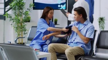 Hasta hipertansiyonu ve kan basıncını ölçen hemşire, hastane bekleme salonunda sağlık muayenesi sırasında tonometreyle kalp muayenesi yapacak. Asyalı danışman yardımcısı, ilaç desteği.