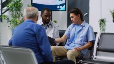 Hastane bekleme odasındaki check-up randevusu sırasında Asyalı hastaya yardım etmek için tıbbi aletle insülin seviyesi ölçümü yapan bir doktor. İlaç destek servisi