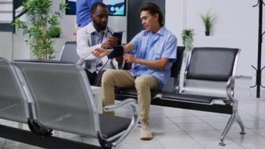 Afrikalı Amerikalı pratisyen doktor genç Asyalı erkek hastaya atardamar gerginliği veriyor. Hastanenin resepsiyonunda nabız ve yüksek tansiyonu ölçmek için tıbbi tonometre kullandık. El kamerasıyla.