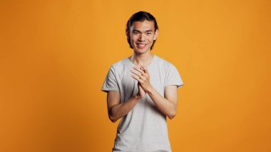 Smiling person clapping hands in studio, laughing and showing natural good emotions. Happy young man applauding and cheering for something, saying congratulations. Standing ovation sign.