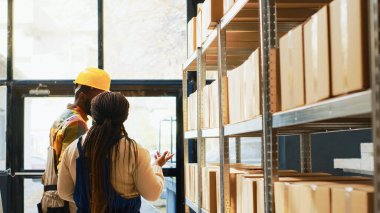 Mal envanteri üzerinde çalışan bir grup insan barkodları tarayıcı ve tabletle tarıyor. Depoda çalışanlar ürünleri ve malları kontrol ediyor..