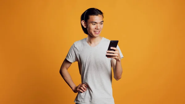 现代年轻人在智能手机上浏览互联网 将手机用于工作室的社交媒体在线网站 无忧无虑的快乐男人在橙色背景下查看浏览器应用程序 — 图库照片