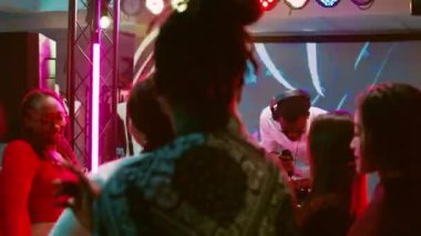 Sahnede yetişkin bir erkek, ses istasyonunu kullanıyor. Diskotekte müziği karıştırıyor. Bir grup arkadaş parti yapıyor ve dans pistinde zıplıyor. Elektronik ritimlerde dans eden genç mutlu insanlar. El kamerasıyla..