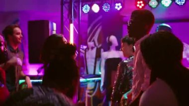 Çeşitli yetişkinler partide eğleniyor. Dans figürlerini funky müzik eşliğinde gösteriyorlar. Toplantının keyfini çıkarıyorlar. Erkekler ve kadınlar dans pistinde dans ediyor, diskotekte mutlu hissediyorlar. El kamerasıyla..