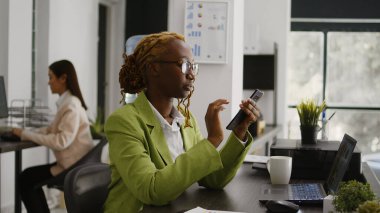 İş yerinde cep telefonu kullanan, masa başı iş planlama yatırımı yapan Afrikalı Amerikalı bir çalışan. Genç yönetici akıllı telefondan sosyal medya uygulamasını kontrol ediyor, kariyer geliştirme.