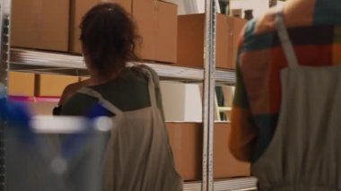 Depo ekibi malları paket halinde gözden geçirir, perakende satış için sipariş vermeden önce ürün kutularını düzenler. Depoda çalışan çeşitli meslektaşlar, hisse senedi lojistiği. El kamerasıyla..