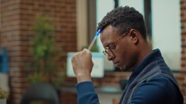 Erkek çalışan iş geliştirme üzerinde çalışmak için vizyon düşünüyor, birlikte çalışma alanında dizüstü bilgisayar ve belgeler kullanıyor. Afrikalı Amerikalı önemli kurumsal bilgileri okuyor..