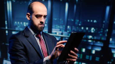 Erkek veritabanı yönetimi veri merkezindeki tablet üzerindeki sunucuyu kontrol ediyor, web dijitalizasyonu için ana bilgisayar işlemcisini analiz ediyor. Bilgi işlem mühendisi büyük veri donanımını inceliyor. El kamerasıyla..