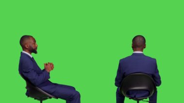 İşletme müdürü sandalyede oturuyor ve birini bekliyor, yeşil perde arkasında resmi ofis elbisesi giyiyor. Şirket çalışanı stüdyoda mutlu ve pozitif hissediyor, genç yetişkin..