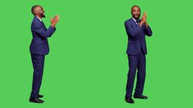 Takım elbiseli, gülümseyen girişimci kamerada alkışlıyor, el çırpıyor ve stüdyoda tebrik ediyor. Resmi işadamı ayakta alkışlıyor, biri için tezahürat yapıyor..