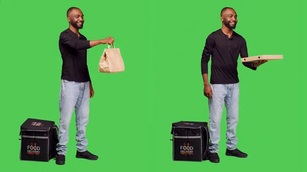アフリカ系アメリカ人は カメラで配達員として働いていて ファーストフードを配達するために熱袋を持っています 男性モデルはテイクアウトバックパックで食事の注文で食品配達従業員としてポーズ — ストック写真