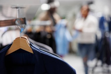 Giyim mağazasında arka planda bulanık askılarda moda ceketler. Alışveriş merkezindeki raflarda asılı yeni koleksiyondan gündelik modern spor ceketler seçici odak noktalarını kapatır