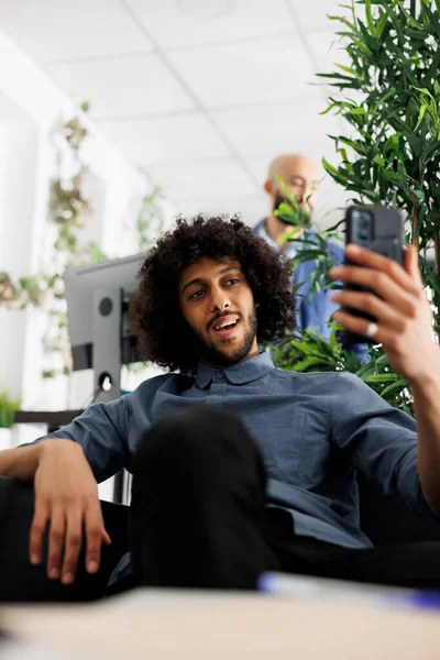 在公司办公室 年轻的Arab男子在智能手机上拥有虚拟视频通信 用手机与同事在线聊天 让新成立的公司员工笑一笑 — 图库照片