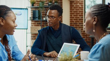 Başlangıçta Afrika kökenli Amerikalılar yeni proje stratejilerini tartışıyor, istatistikleri ve şirket sonuçlarını kağıtlarla inceliyorlar. İdari çalışanlardan oluşan bir ekip beyin fırtınası yapıyor..