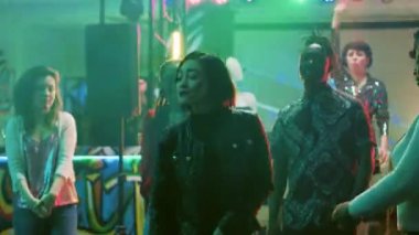 Kadın dansçı gece kulübünde eğleniyor, müzik eşliğinde dans etmekten mutlu oluyor. Dans pistinde dans figürleri gösteren, disko ışıklarıyla parti yapan bir grup insan. Üçayak atışı.