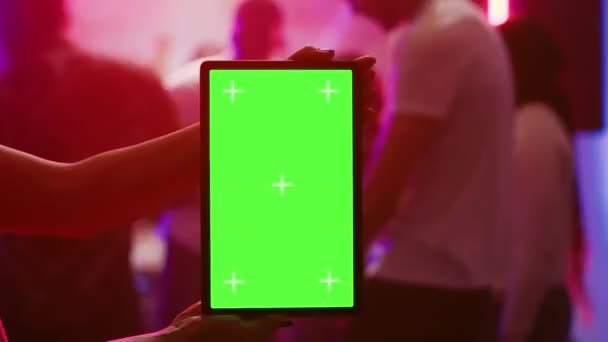 ダンスフロアのパーティーで空白のクロマキーディスプレイを保持しているクラブで緑の画面表示を示す女の子 デバイス上のコピースペーステンプレートと隔離されたモックアップ画面を使用して現代人 三脚ショット — ストック動画