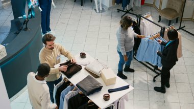Çeşitli müşteriler butik dükkanından mal alıyor, alışveriş merkezindeki elbise koleksiyonlarını kontrol ediyor. İnsanlar resmi ya da günlük giysiler için alışveriş yapıyorlar, yeni moda markalar..