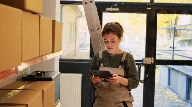 Kalite kontrolü yapmadan önce merkezle konuşan sabit hatlı bir kadın. Sipariş sevkiyatı ve teslimat için malları denetleyen genç bir yetişkin. Küçük işletme üretimi..
