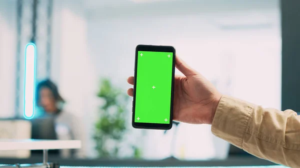 携帯電話を緑色の画面で使用している若い従業員は スマートフォン上で隔離されたコピースペース表示を示します ブティックでブランククロマキーモックアップテンプレートを保持男性ストアアシスタント 閉じろ — ストック写真