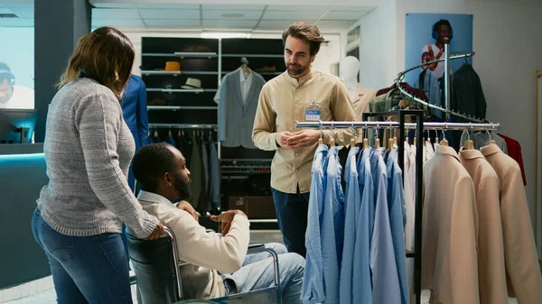 障害のあるアフリカ系アメリカ人男性が小売店を訪問し 衣料品店で流行のファッションコレクションのためのショッピング 男性車いすユーザー 市場ブティックからカジュアルウェアを購入 — ストック写真