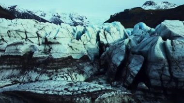 İzlanda 'daki Vatnajokull buz tabakasındaki mavi buzulların havadan görünüşü, elmas şekilli buz kalıpları. Muhteşem buzdağları ve yarıklar inanılmaz İskandinav manzarası oluşturuyor. Yavaş çekim.
