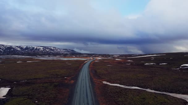 雪山与冰原结冰的田野之间的大路 无人驾驶飞机拍摄的冰山一角 风景优美 斯堪的纳维亚风景线 有山丘 冬季风景 — 图库视频影像