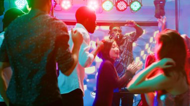 Diskotekteki DJ müzik istasyonundan çeşitli arkadaş grupları elektronik müzik eşliğinde dans ediyorlar. Eğlenceli insanlar parti yapıyor ve modern müzik seslerini, renkli diskoları seviyor..