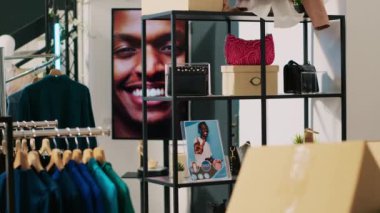Moda aksesuarlarla dolu modern bir butik, modaya uygun ürünlerle dolu birden fazla raf. Askıda şık kıyafetler olan boş giyim mağazasının içi, küçük işletme konsepti..
