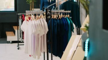 Gündelik ve resmi giysi ürünleri olan boş modern butik, askılarda ve raflarda şık giysileri olan perakende mağazası. Alışveriş merkezinin içindeki giyim mağazası, şık mallar ve aksesuarlar..