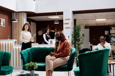 Salon ve lobide çalışanları ve misafirleri olan bir otel müdürü. Resepsiyondaki otel hizmetlerini ve kayıt işlemlerini kontrol eden zarif bir yönetici. Kalacak yer müdürü olarak çalışan bir kadın..