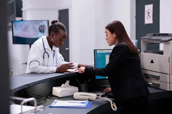 Recepcjonistka Azjatycka Rozmawia Lekarzem Recepcji Szpitala Omawiając Specjalistyczną Wiedzę Temat — Zdjęcie stockowe