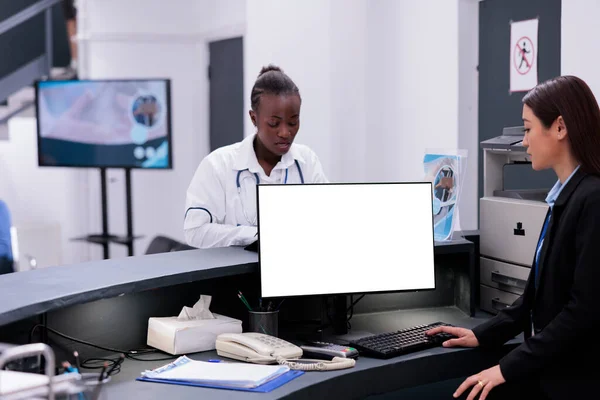 接待员在医院接待处使用带有白色隔离屏风的计算机 在检查期间使用模拟模板工作的设施工作人员 帮助病人预约 — 图库照片
