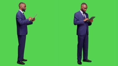 Tablet üzerinde internet sitesine göz atmak, tam vücut yeşil ekran arkaplanı üzerinde çevrimiçi ağ sayfası üzerinde çalışmak. Ofis kıyafetli genç bir adam stüdyoda alet tutuyor..