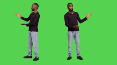 Afro-amerikan bir adam reklam sunumu için stüdyoda reklam hazırlıyor. Kot pantolonlu ve gömlekli genç bir erkek model tüm vücudunu yeşil ekrana yansıtıyor..